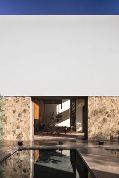 an empty swimming pool in front of a stone wall and glass door that leads to the outside