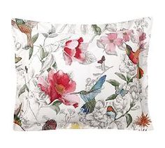 a white pillow with pink flowers and birds on the front, along with a red hummingbird