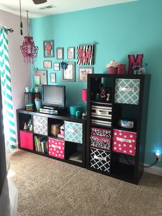 a living room with blue walls and lots of colorful storage boxes on the shelves in front of it