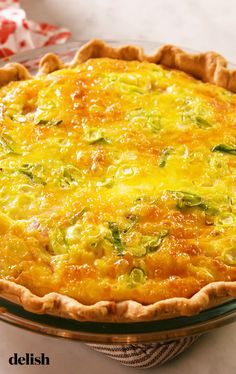 a quiche with cheese and broccoli in a glass pie dish on a table