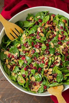 spinach salad with cranberries and almonds in a white bowl on a wooden table