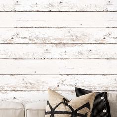 a couch with two pillows on top of it next to a wall made out of wood planks