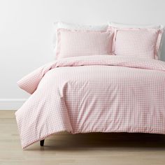 a pink and white checkered comforter set on a bed with two pillow cases