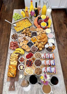 a table filled with lots of food on top of a wooden floor next to bottles of juice