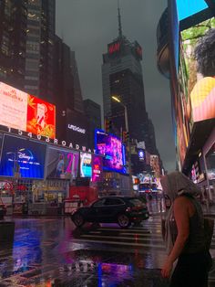 a city street at night with cars and billboards on the buildings in the rain