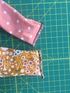 two pieces of fabric sitting on top of a green cutting board next to each other