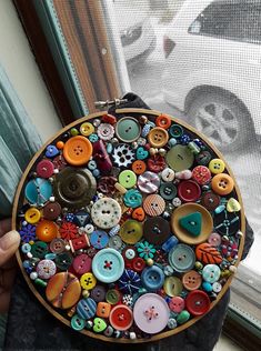 a person holding a plate with buttons on it in front of a window sill