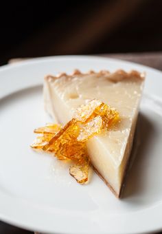 a piece of pie on a white plate with orange zest garnishes