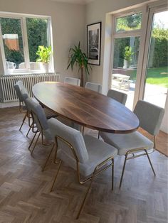 a large wooden table surrounded by chairs in a room with wood flooring and windows