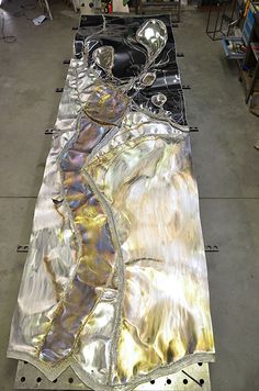 an art piece is being worked on in a factory area with other metal parts and tools