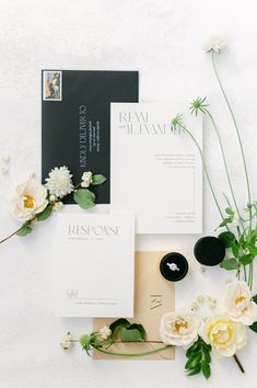 the wedding stationery is laid out on top of each other with flowers and greenery