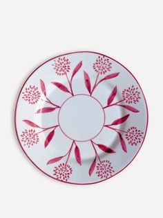 a red and white plate with flowers on it's rim, against a white background