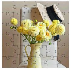 a vase filled with yellow flowers sitting on top of a white table next to a puzzle piece