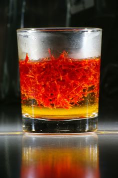 a glass filled with liquid sitting on top of a table