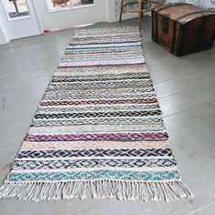 a multicolored rug with fringes on the floor