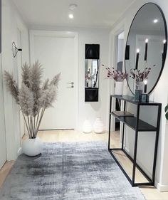 a room with a rug, mirror and vase on the floor