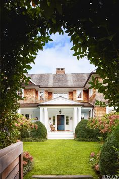 a large white house sitting in the middle of a lush green field next to a wooden gate