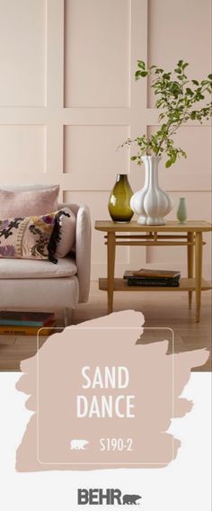 a couch and table with vases on it in front of a pink wall that says sand dance