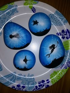 four painted rocks sitting on top of a white plate