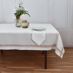 a table with a vase and plate on it next to a white cloth covered tablecloth