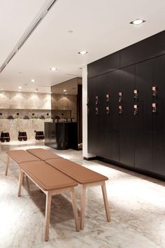 an empty room with tables and lockers on the wall, in front of a row of chairs