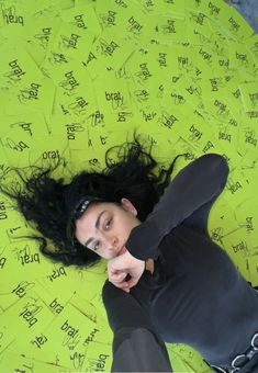 a woman laying on top of a yellow floor covered in writing and papers with words written all over her body