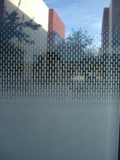 the reflection of a building and trees in a glass window with an abstract pattern on it