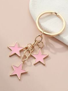 three pink stars are hanging from a gold keychain