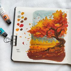 an open book with watercolors and markers next to it