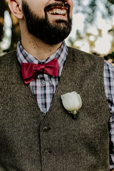 a man wearing a vest and bow tie with a flower in his lapel pocket