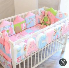 a baby crib with pink, blue and green bedding on the bottom row