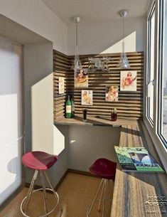 two red chairs sitting in front of a counter next to a window with pictures on it