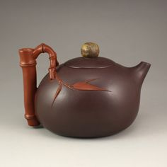 a brown teapot with a bamboo handle is shown in front of a gray background