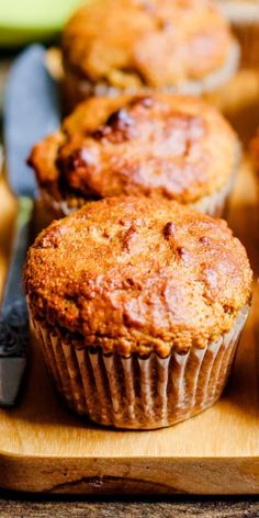 three muffins sitting on top of a wooden cutting board