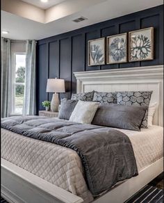 a large bed sitting in a bedroom next to a window with two pictures above it