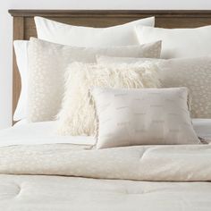 a bed with white sheets and pillows on it