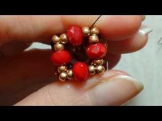 a person holding a red beaded ring with gold bells on it's end