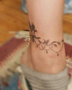 a woman's foot with a flower tattoo on the side of her leg and ankle