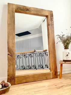 a wooden mirror sitting on top of a hard wood floor next to a potted plant