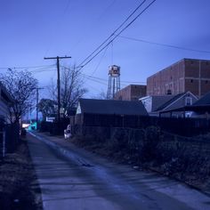 an empty street with houses and water tower in the background