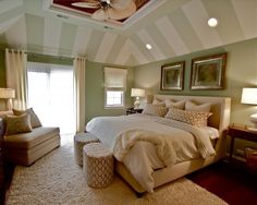 a bedroom with green walls and white carpeted flooring, large bed surrounded by beige furniture