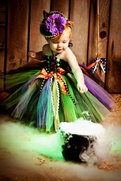 a baby girl wearing a green and purple dress