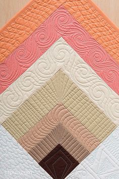 a close up of a quilt on a table top with many different colors and shapes