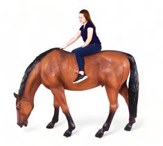 a woman riding on the back of a brown horse next to a white background in front of her