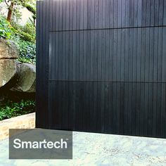 a black wooden fence in front of some rocks and trees with the words smarttech on it