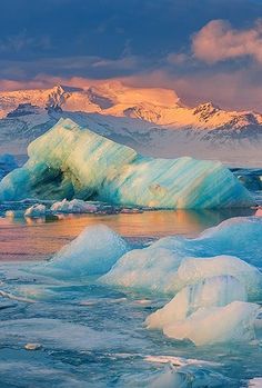 icebergs floating on the water with mountains in the background