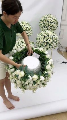 a woman placing flowers on a wreath