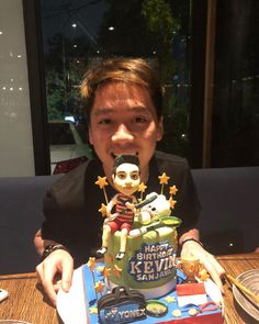 a man sitting at a table with a cake in front of him and an action figure on top