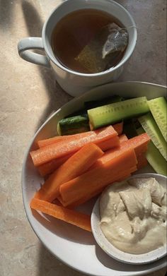 carrots, cucumbers and celery on a white plate with dip