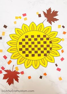 the paper sunflower is surrounded by fall leaves